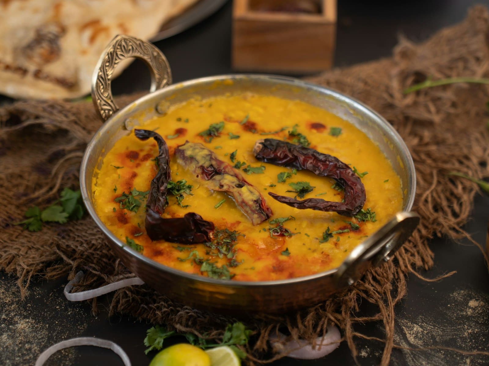 A bowl of yellow dal topped with a tempering of dried red chilies and spices
