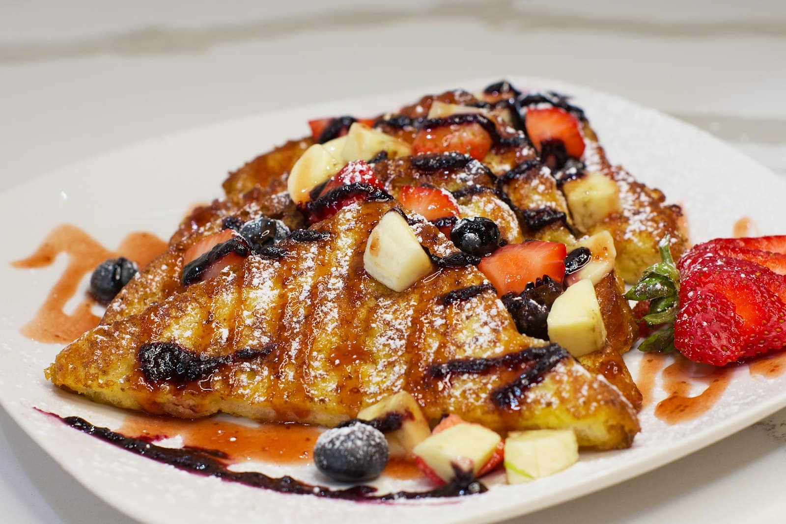 French toast topped with strawberries, blueberries and banana