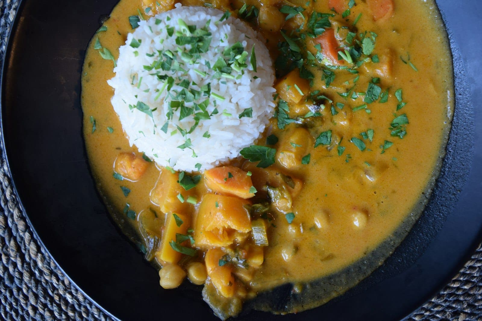 A golden chickpea and vegetable curry served with a mound of rice