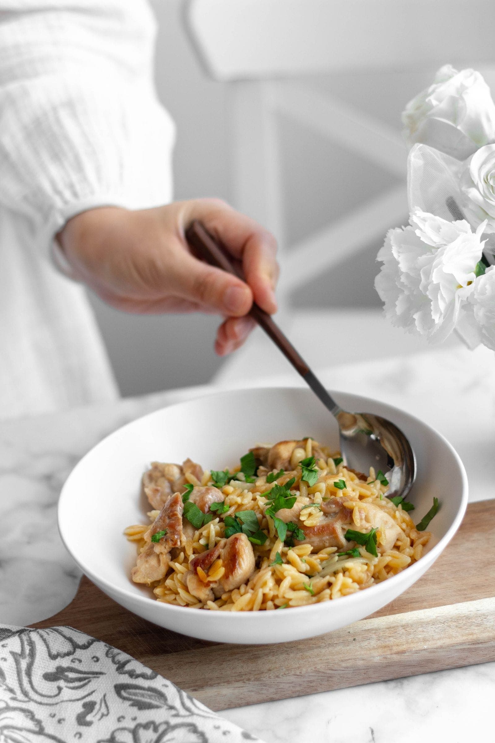 A bowl of orzo with chicken and parsley