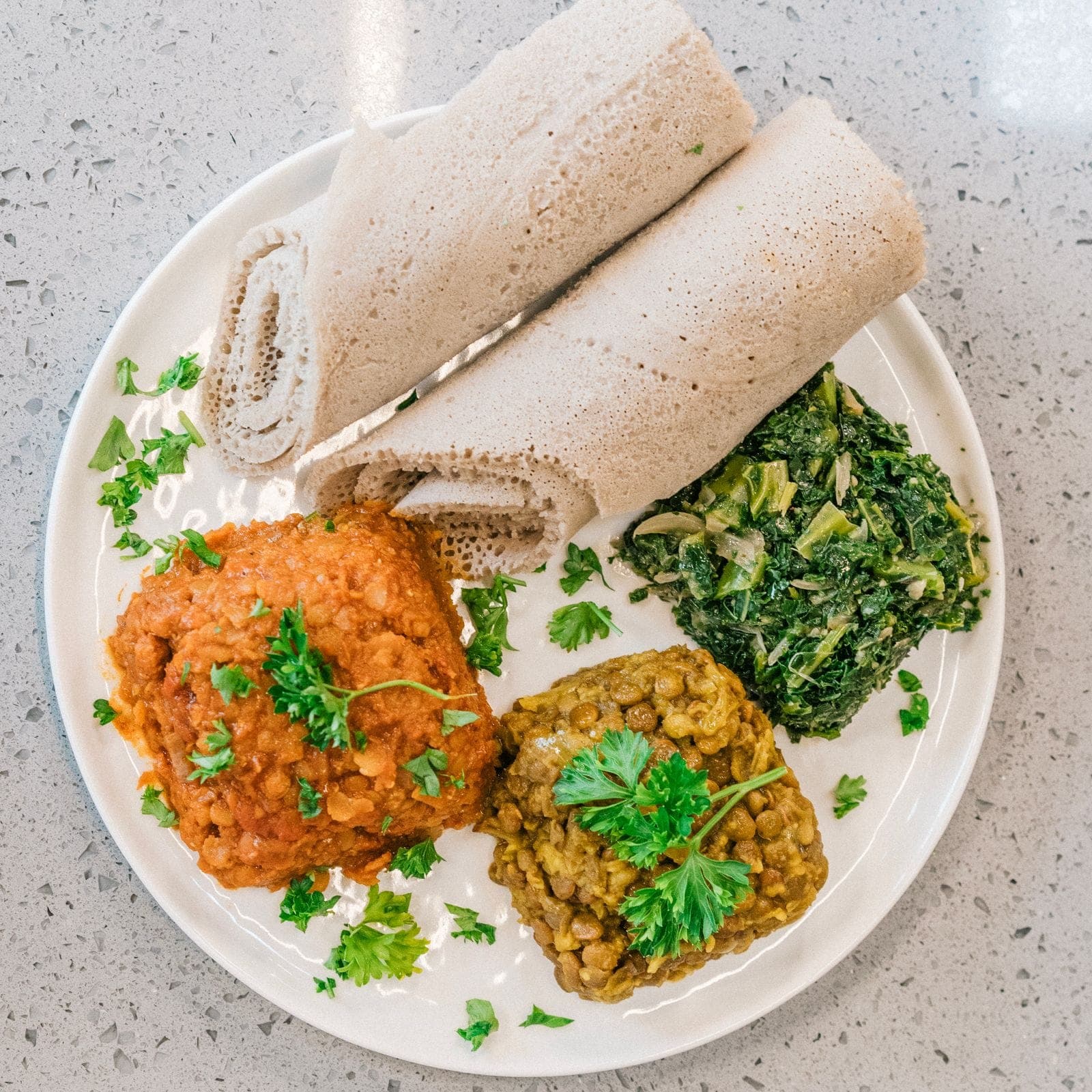 An Ethiopian plate of red lentil misir wot, lentils and collard greens with injera