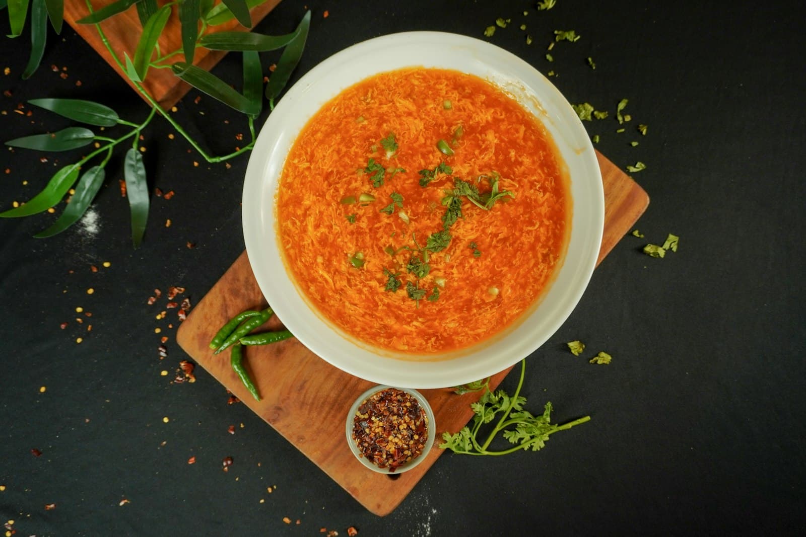 A bowl of orange red lentil soup garnished with fresh herbs