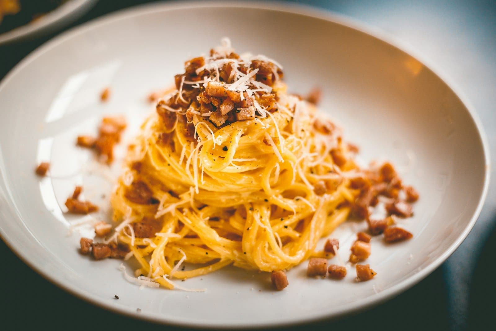 A swirl of spaghetti carbonara topped with crisp pork and grated cheese