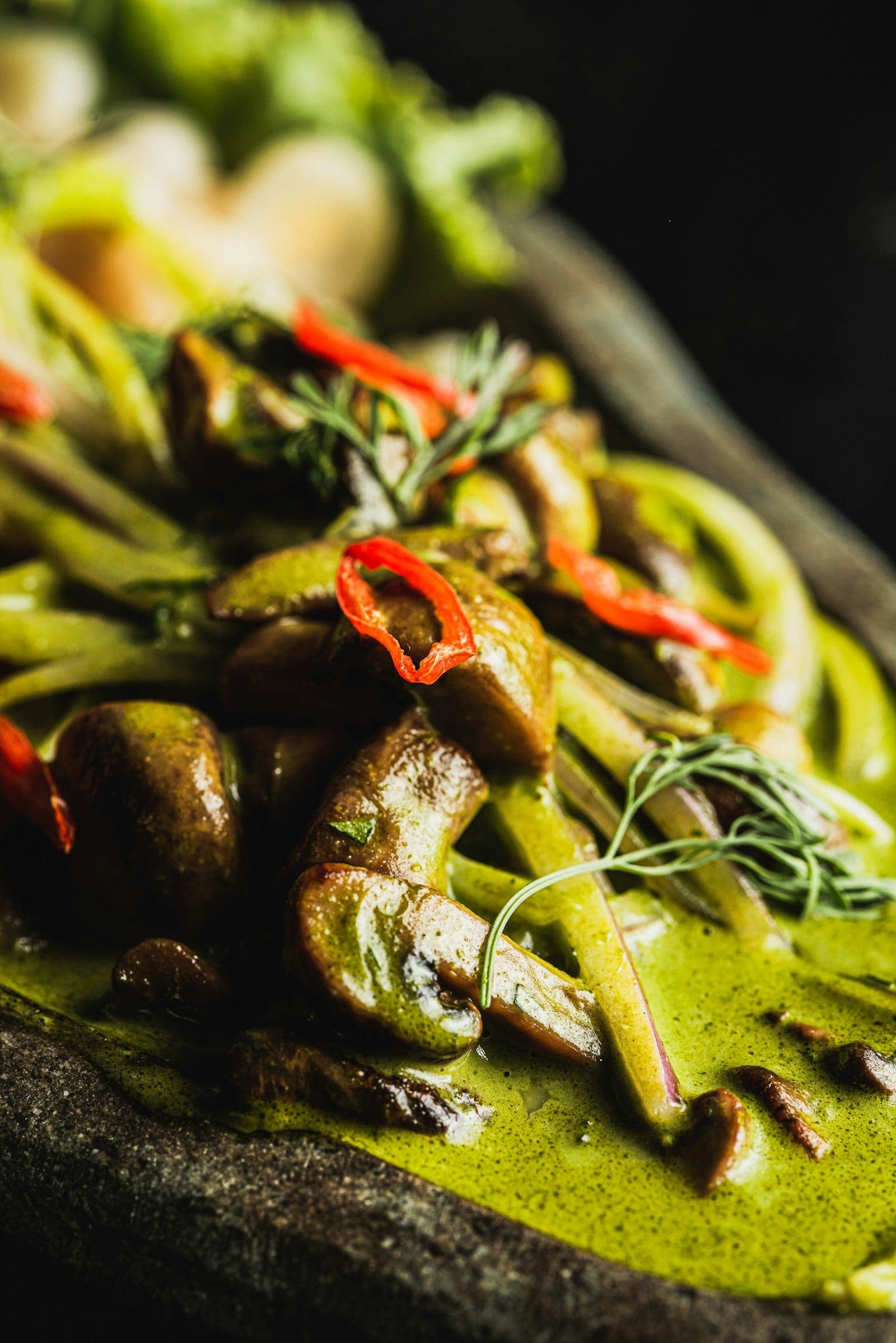 Close-up of Thai green curry with mushrooms and sliced red chili