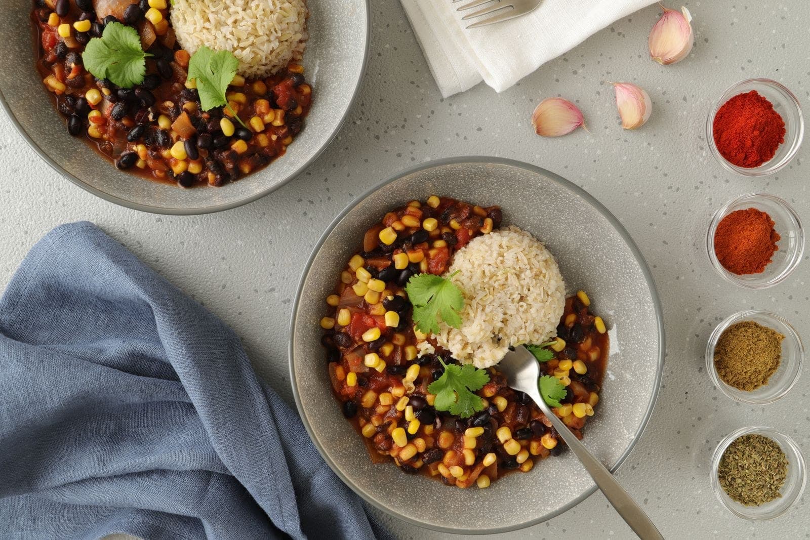Bowls of vegan bean chili with corn, served with rice