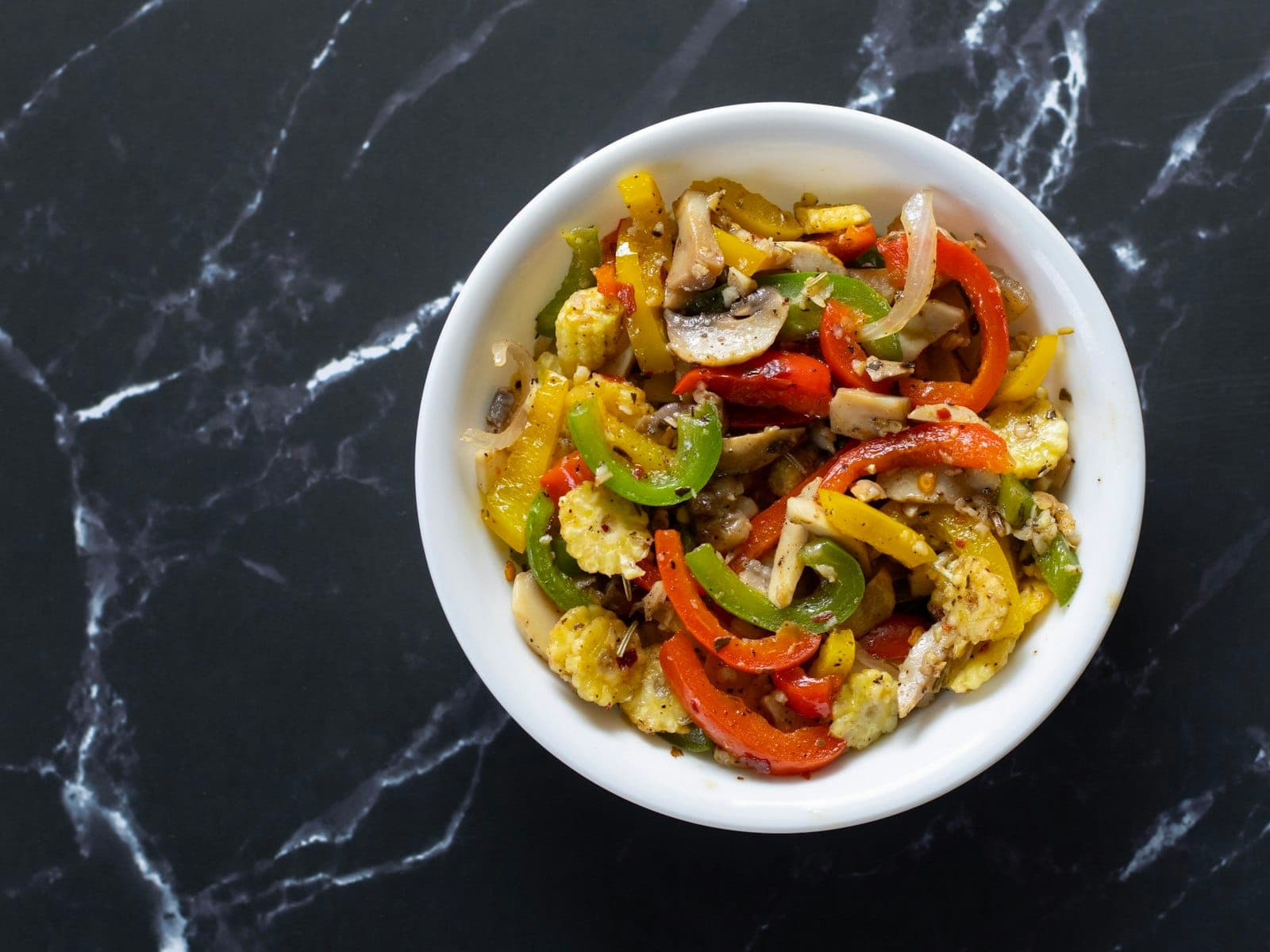 A bowl of sautéed bell peppers, onions, mushrooms and baby corn
